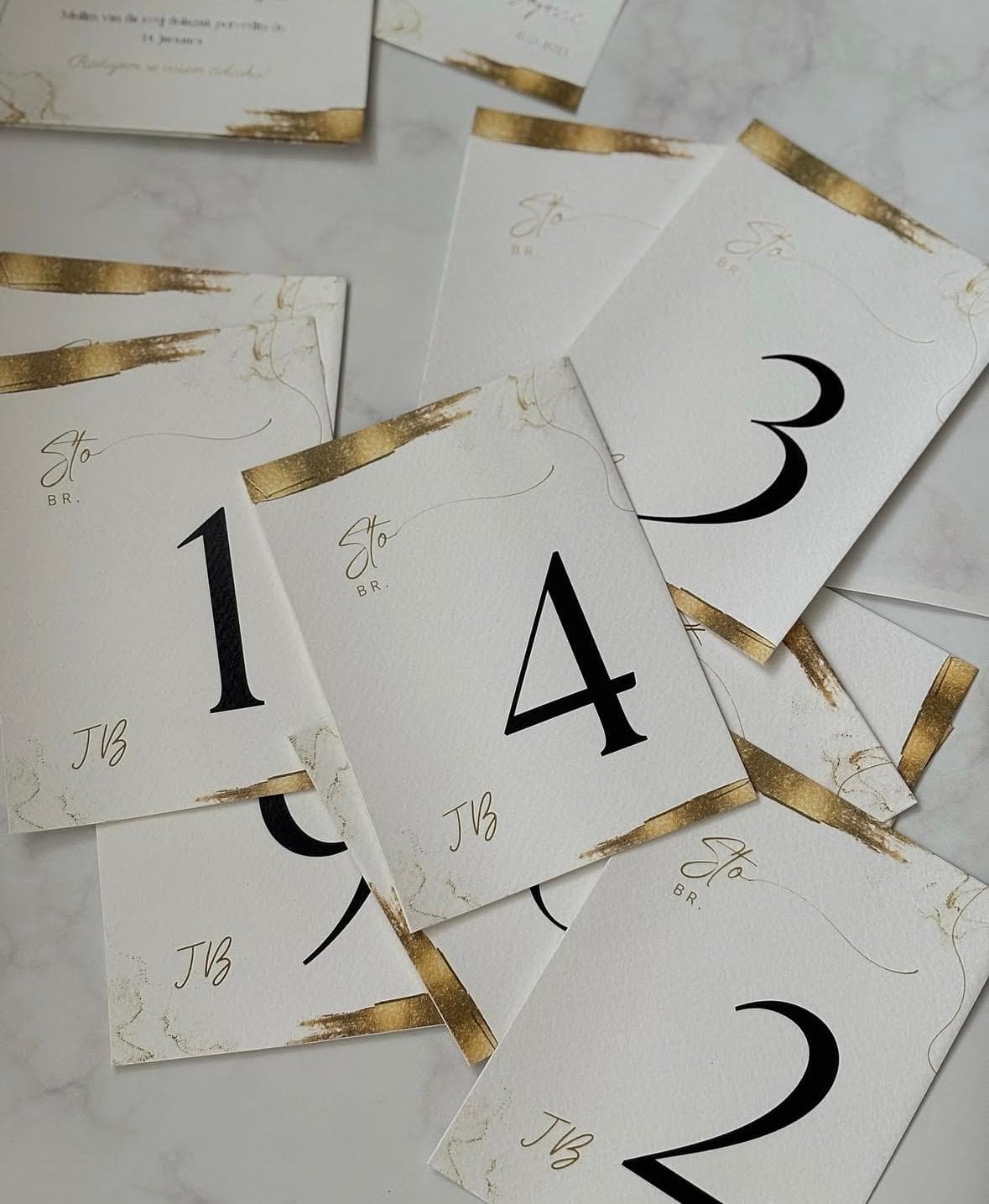 Elegant table number cards in gold and white for wedding or event decor, matching the "Brojevi za st.