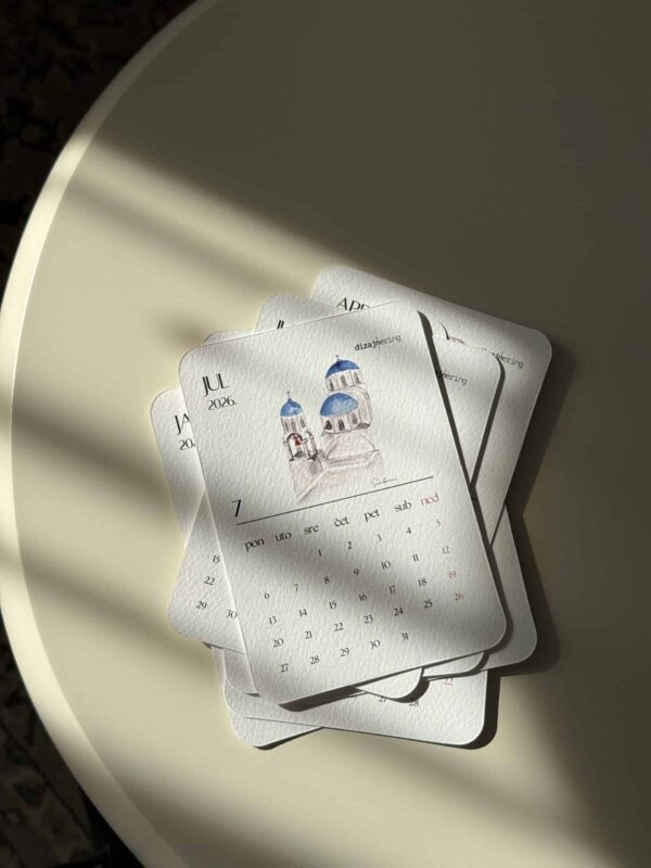 Colorful illustrated calendar pages with blue domes and hand-drawn architecture, on a white round table.