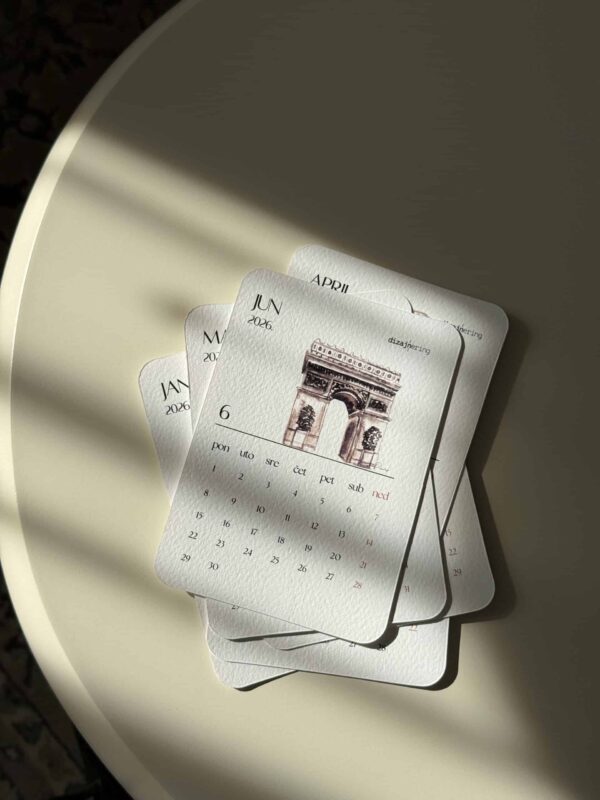 Colorful 2026 calendar featuring the Arc de Triomphe, placed on a white surface with soft shadow effects.