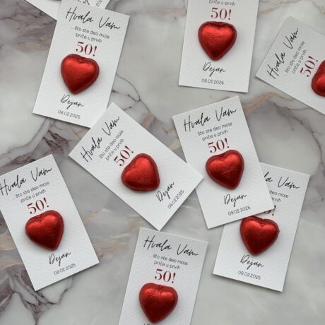 Red heart-shaped tokens attached to thank you cards celebrating 50th birthday.