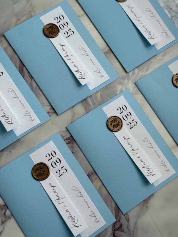 Stylish wedding invitation card with blue background, white ribbon, and gold wax seal for elegant ce.