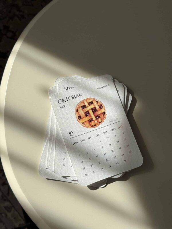 Delicate calendar pages with pie illustrations aligned on a white surface under soft light.