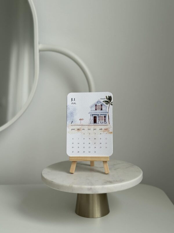 Minimalist house-themed desk calendar on a small wooden easel, modern interior decor, neutral color palette, July 2026.