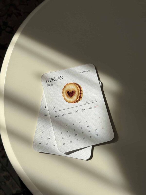 Delicate February 2023 calendar with cookie illustration on bright table, minimalist design.