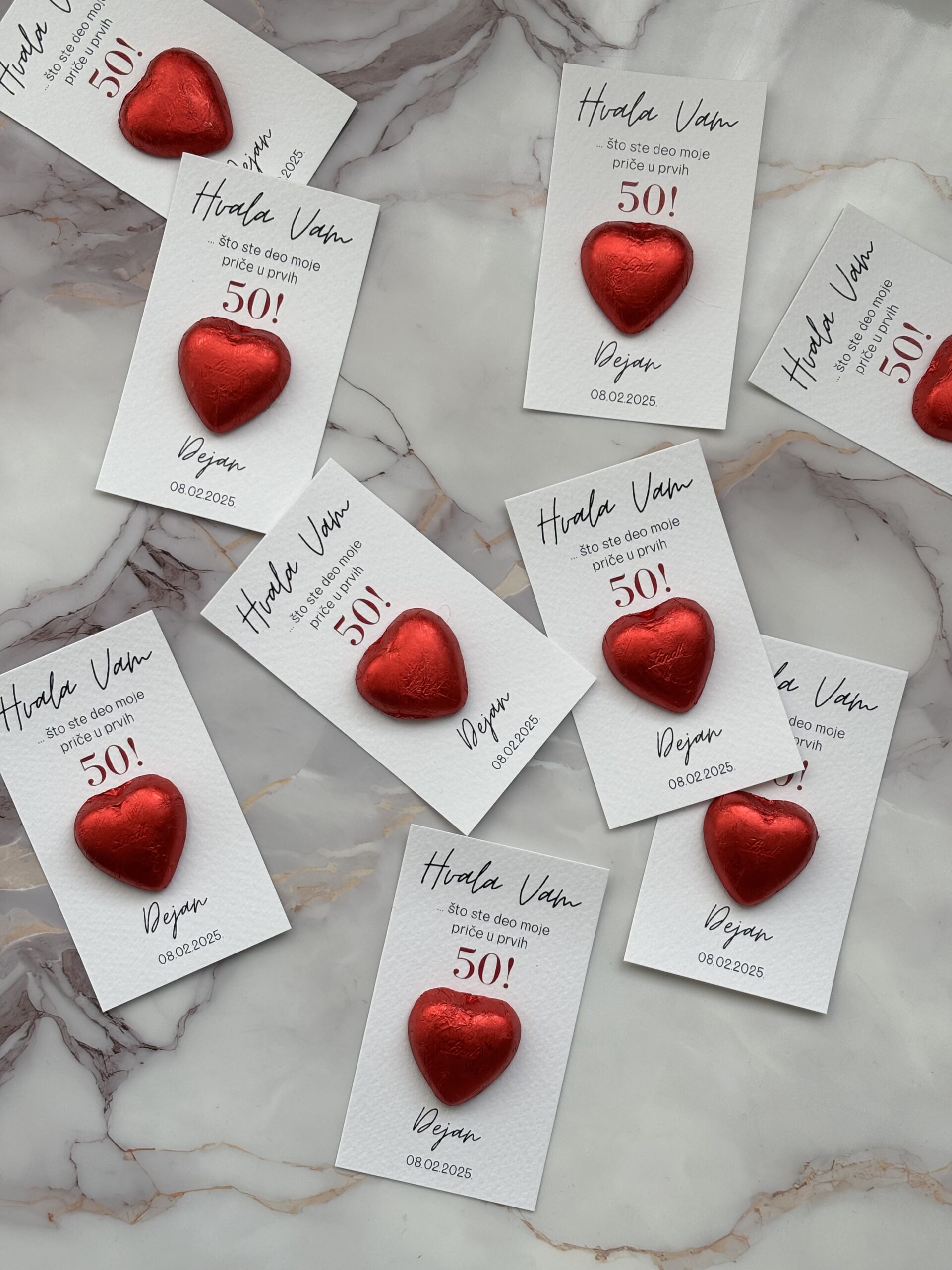 Red heart-shaped tokens attached to thank you cards celebrating 50th birthday.
