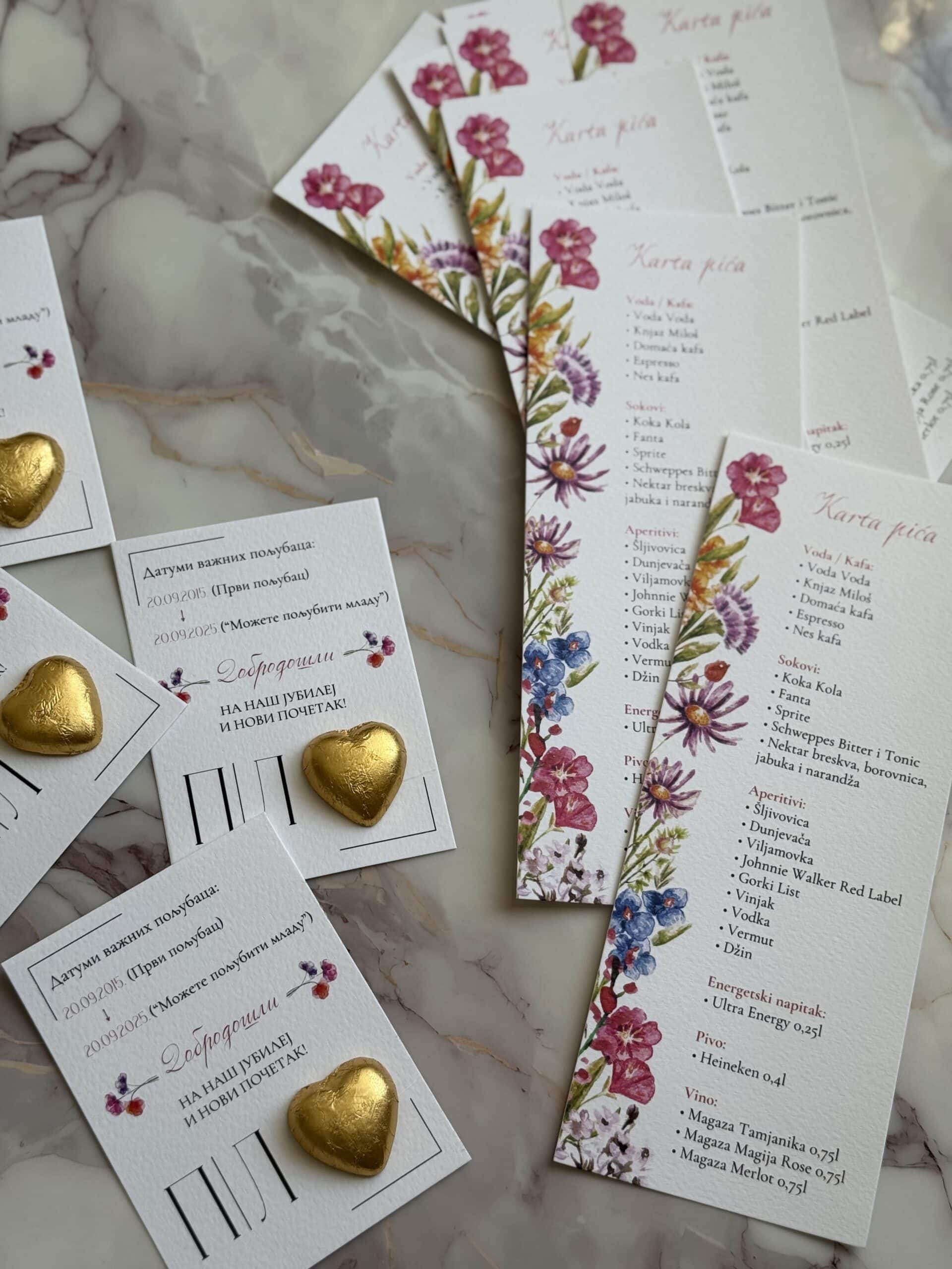 Vibrant floral-themed wedding menu and table cards with gold heart decorations, perfect for elegant event decor.